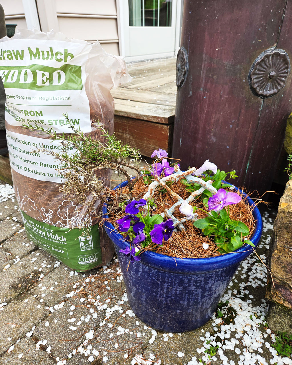 Shredded Pine Straw Organic Mulch Bag next to Pot with Pansies